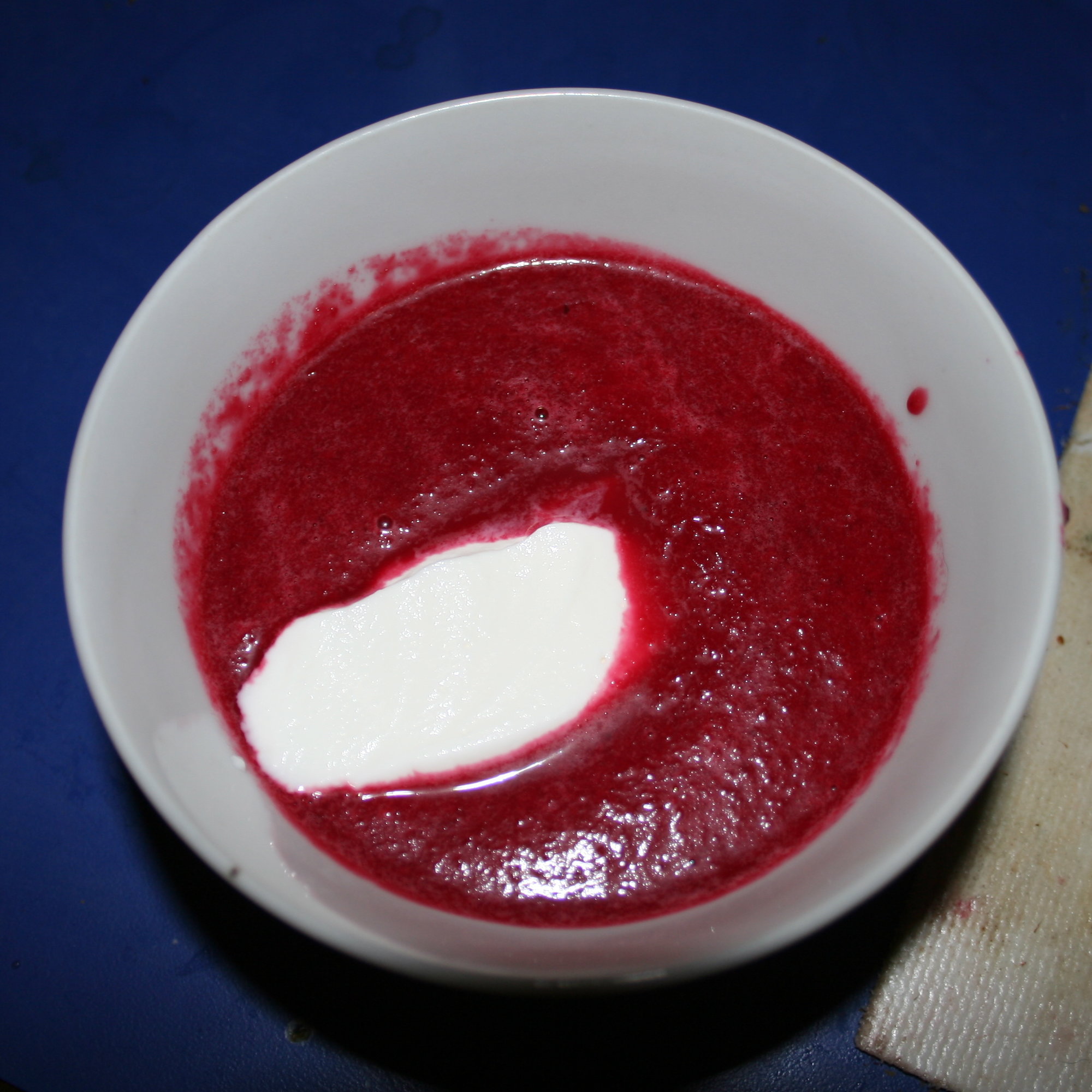A cup of borscht topped with sour cream