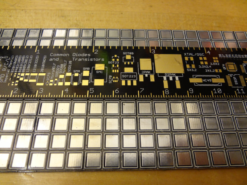 A panel of QRPme MeSQUARE pads with a ruler laid on top for scale.  Each pad is about 6x6 mm square.