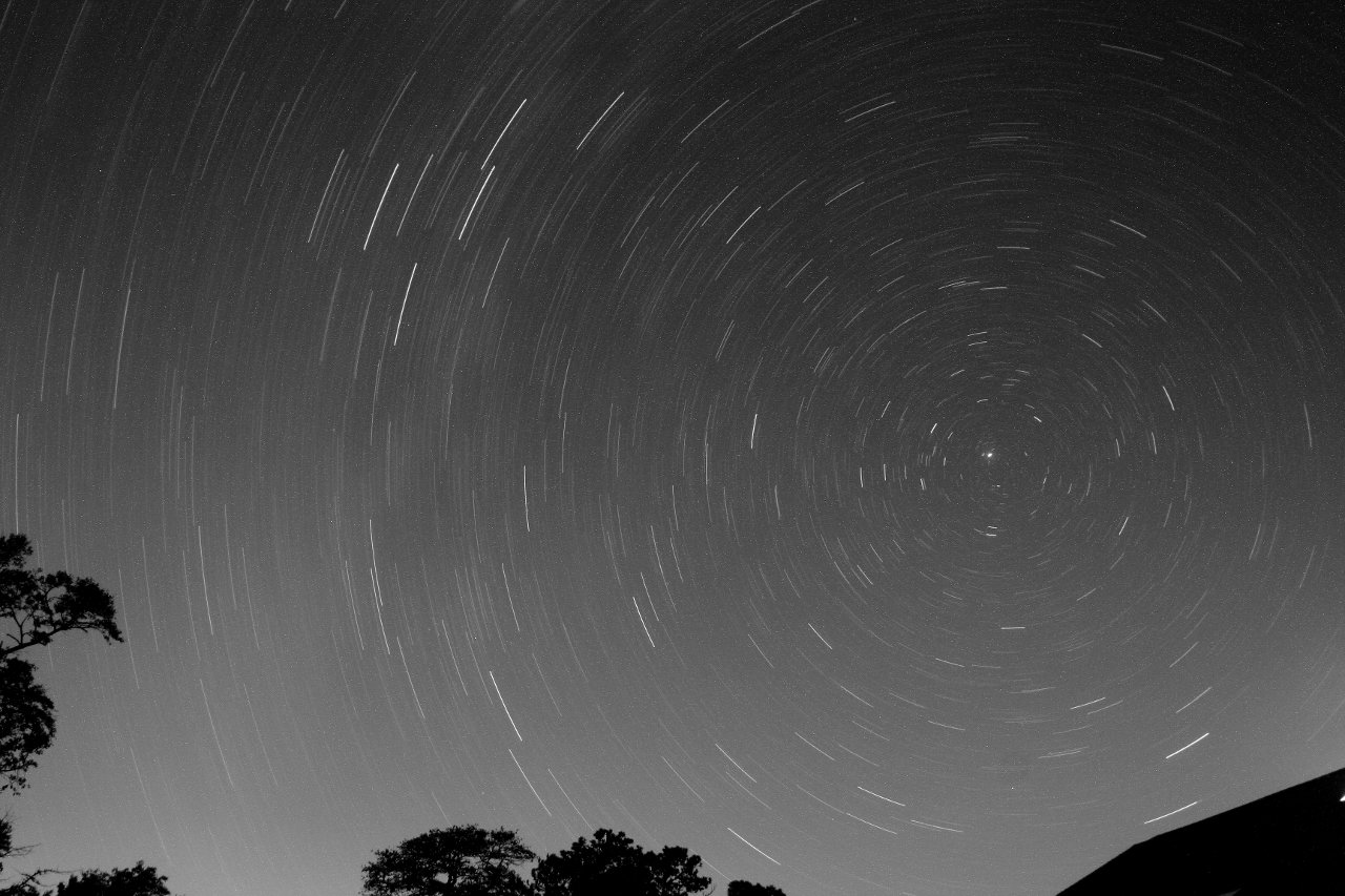 Long exposure of the sky showing star trails curving around the North Star