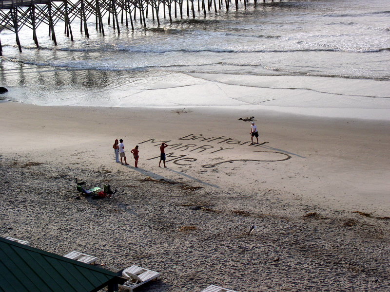 A marriage proposal written in large letters in the sand at the beach