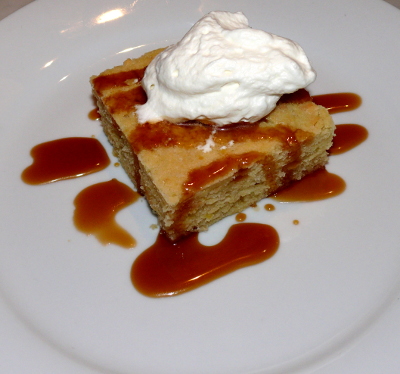 Lemon pudding cake.  A square of cake topped with a dollop of whipped cream and a drizzle of red sauce