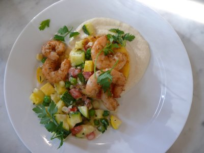 A plate of grilled domestic shrimp with truffled summer succotash, crisp parmesan grit cake with cauliflower buttermilk puree