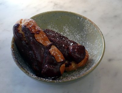 A bowl with two chocolate covered banana eclairs